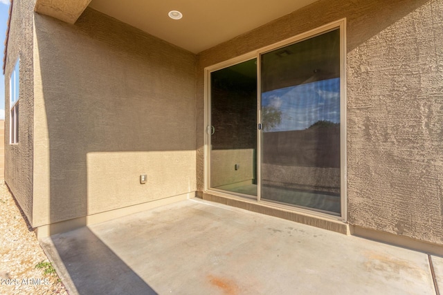 view of exterior entry featuring a patio area and stucco siding