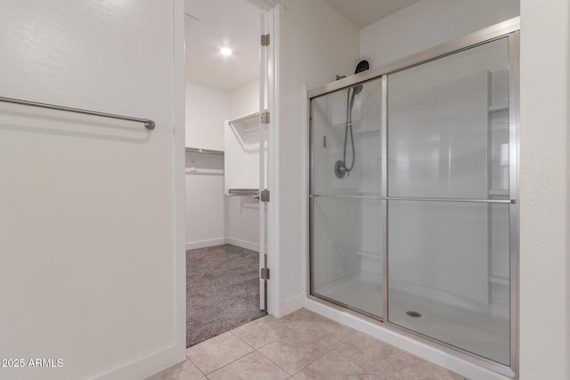 bathroom with baseboards, tile patterned flooring, a shower stall, and a spacious closet