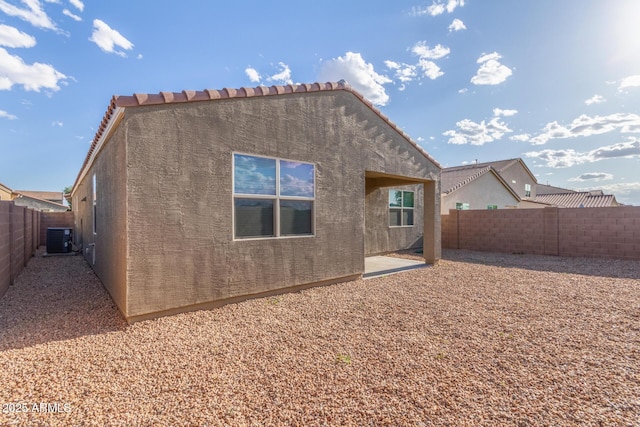 back of house with stucco siding, a fenced backyard, a patio area, and central air condition unit