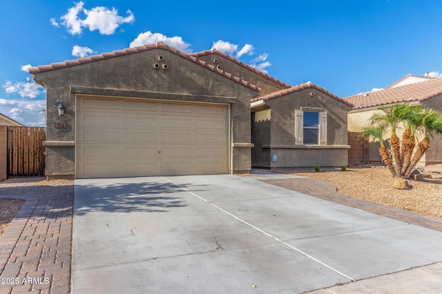 view of front of property with a garage, fence, stucco siding, a tiled roof, and driveway