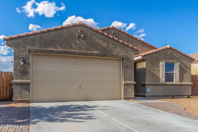 mediterranean / spanish-style home featuring a tiled roof, an attached garage, driveway, and stucco siding
