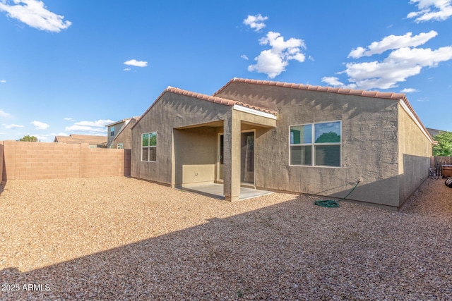rear view of property with a patio, a fenced backyard, stucco siding, and a tiled roof