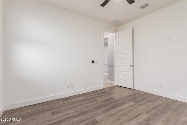 spare room with visible vents, a ceiling fan, baseboards, and wood finished floors