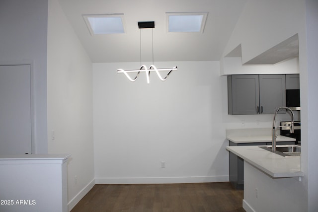 kitchen with dark wood-type flooring, baseboards, light countertops, gray cabinets, and a sink