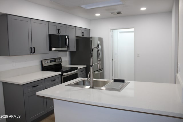 kitchen with a sink, stainless steel appliances, visible vents, and gray cabinets