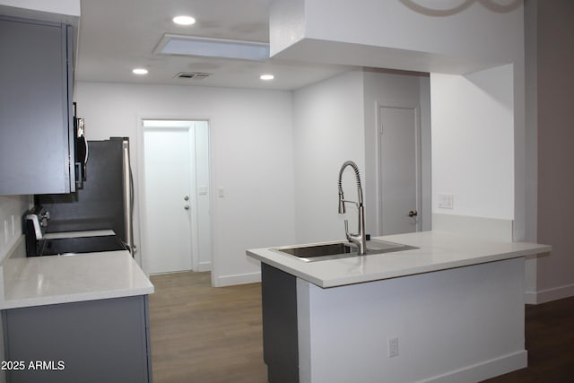 kitchen featuring visible vents, gray cabinets, a sink, range with electric stovetop, and dark wood-style floors