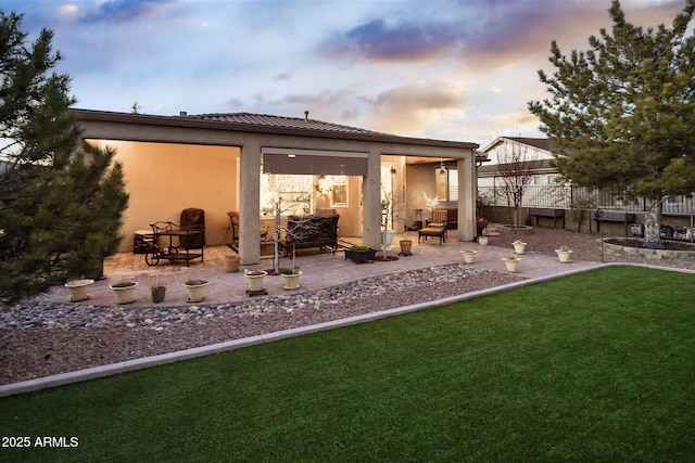 6975 E Lynx Wagon Rd, Prescott Valley, AZ 86314 - back of house at dusk featuring a patio, a lawn, fence, and stucco siding