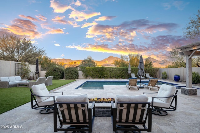 pool at dusk with a patio area, a mountain view, and outdoor lounge area