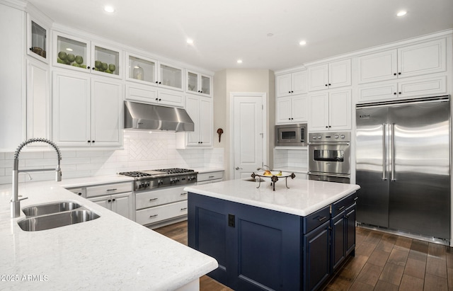 kitchen featuring blue cabinetry, built in appliances, light stone counters, white cabinets, and sink