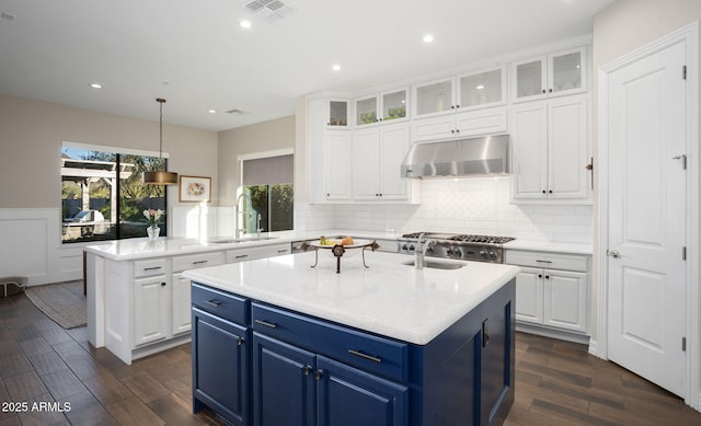 kitchen featuring sink, hanging light fixtures, blue cabinets, and a kitchen island with sink