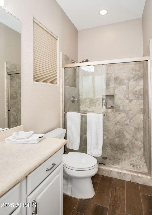 bathroom featuring toilet, an enclosed shower, and vanity