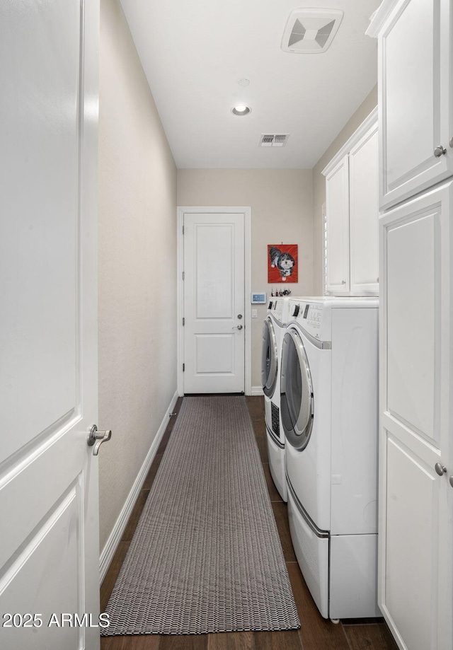 clothes washing area with washer and dryer, cabinets, and dark hardwood / wood-style floors