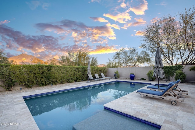 pool at dusk with a patio and a mountain view