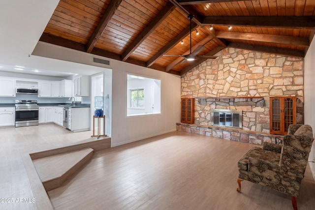 405 E Stanford Ave, Gilbert, AZ 85234 - unfurnished living room featuring wooden ceiling with exposed beams, a sink, a ceiling fan, light wood finished floors, and a stone fireplace