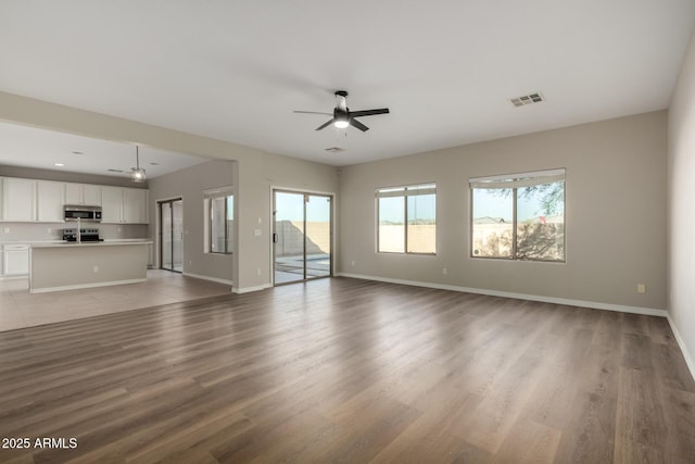 unfurnished living room with ceiling fan and wood-type flooring