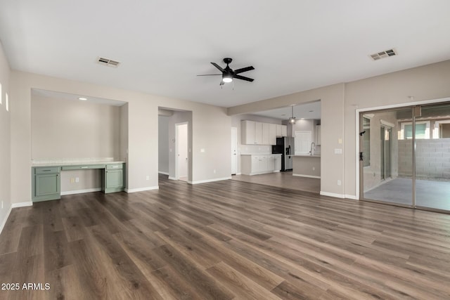 unfurnished living room featuring ceiling fan, sink, and dark hardwood / wood-style flooring