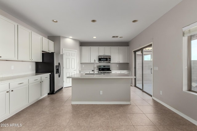 kitchen featuring appliances with stainless steel finishes, a kitchen island with sink, light tile patterned flooring, white cabinets, and sink