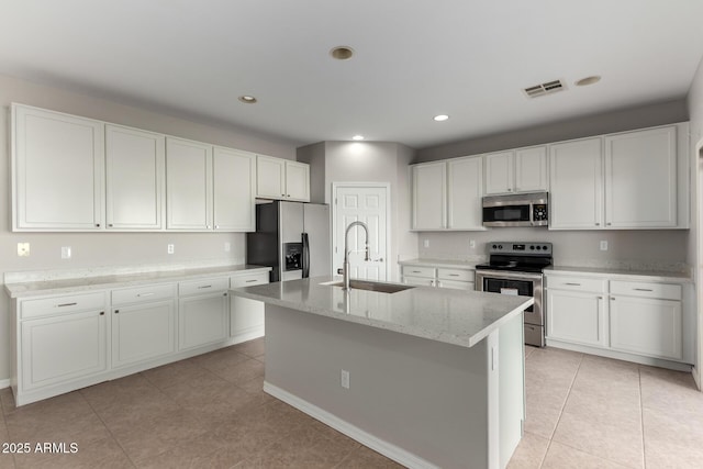 kitchen featuring light tile patterned floors, white cabinetry, appliances with stainless steel finishes, a kitchen island with sink, and sink