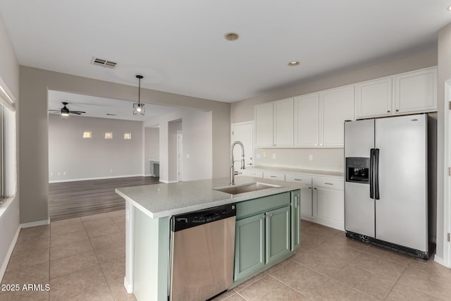 kitchen with white cabinetry, stainless steel appliances, a kitchen island with sink, green cabinetry, and sink