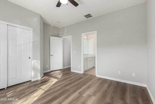 unfurnished bedroom with ceiling fan, ensuite bathroom, a closet, and hardwood / wood-style floors