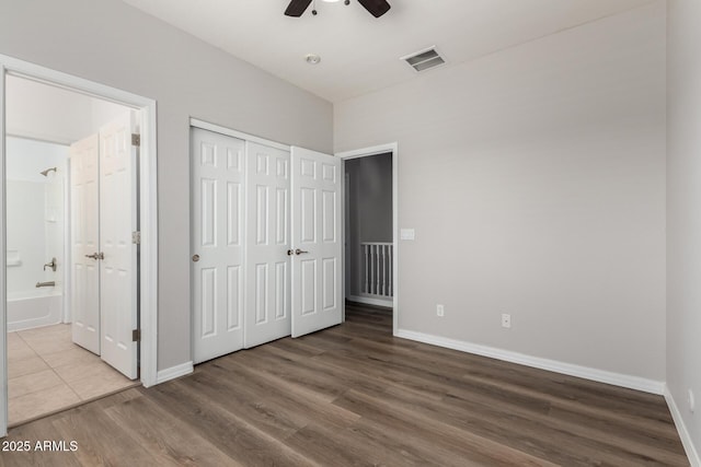 unfurnished bedroom with ceiling fan, hardwood / wood-style flooring, a closet, and ensuite bath