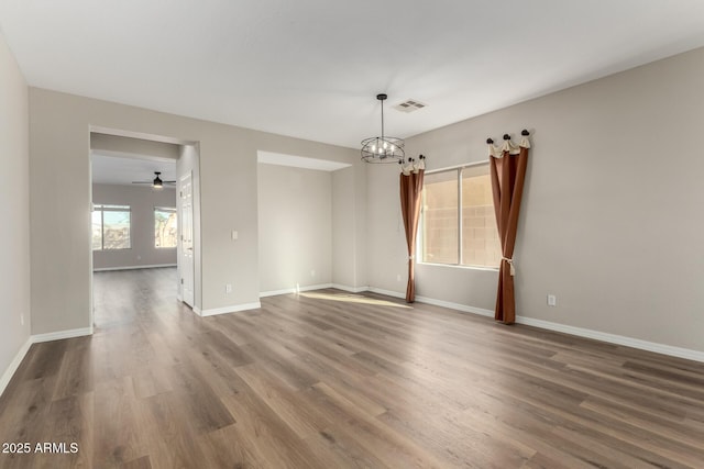 spare room featuring ceiling fan with notable chandelier and wood-type flooring