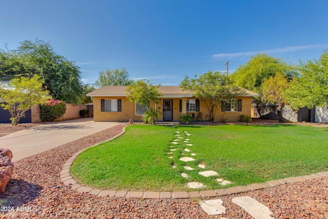 ranch-style house featuring a front yard, fence, concrete driveway, and stucco siding