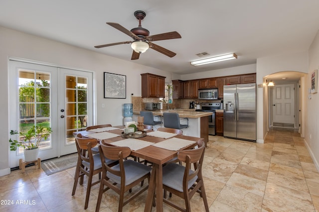 dining space featuring arched walkways, ceiling fan, visible vents, baseboards, and french doors