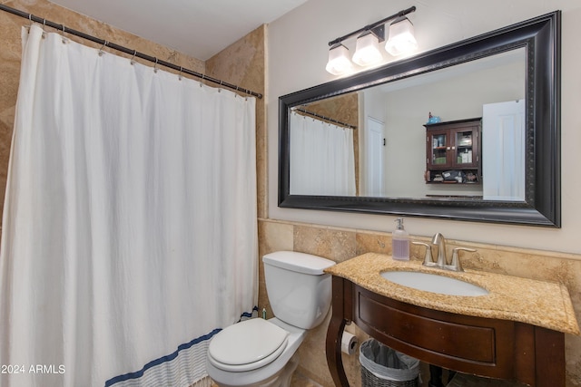 bathroom with toilet, vanity, tile walls, wainscoting, and a shower with curtain