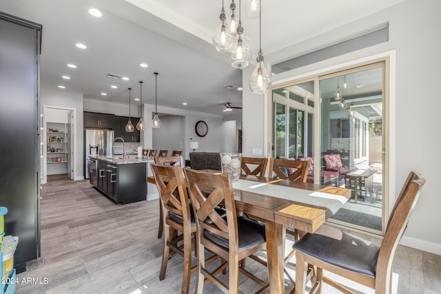 dining room with light hardwood / wood-style floors, ceiling fan, and sink