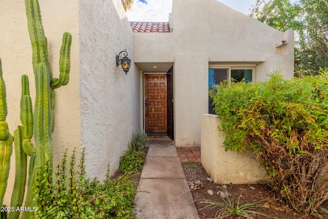 entrance to property featuring stucco siding and a tile roof