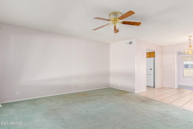 carpeted empty room featuring ceiling fan with notable chandelier and a textured ceiling