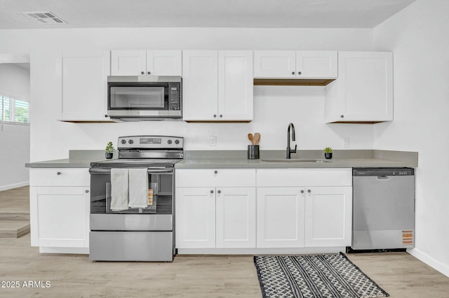 kitchen featuring a sink, stainless steel appliances, visible vents, baseboards, and white cabinets