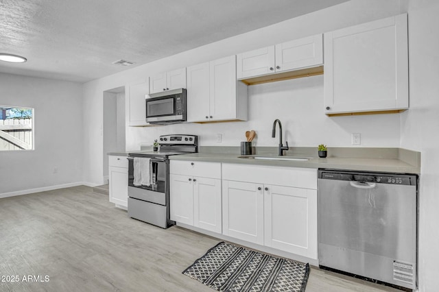 kitchen featuring visible vents, appliances with stainless steel finishes, a sink, white cabinetry, and light wood-type flooring