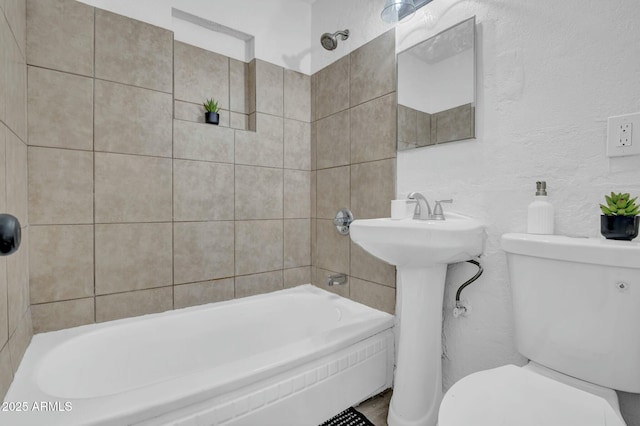 full bath with a textured wall, toilet, tub / shower combination, and a sink