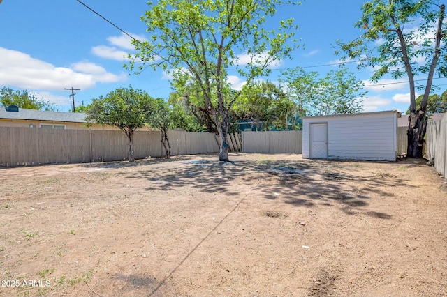 view of yard featuring a storage shed, an outdoor structure, and a fenced backyard