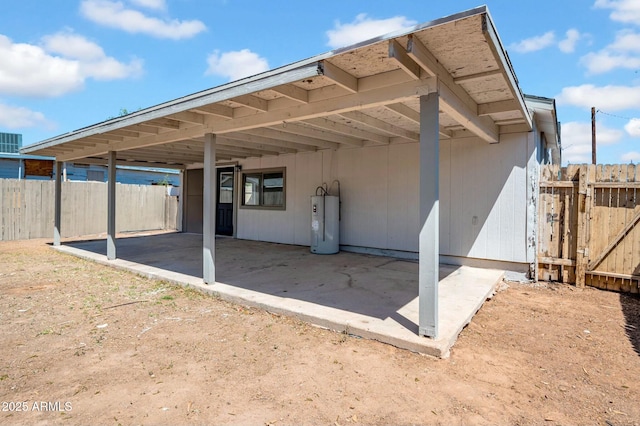 rear view of house featuring fence, a carport, water heater, and a gate