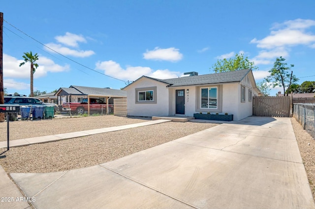 single story home featuring a shingled roof, fence, stucco siding, and concrete driveway