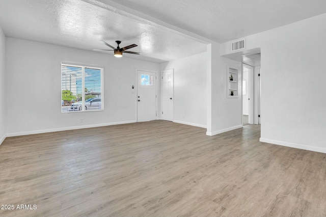 unfurnished living room with a textured ceiling, visible vents, ceiling fan, baseboards, and wood finished floors