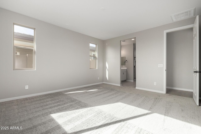 unfurnished bedroom featuring light carpet and ensuite bath