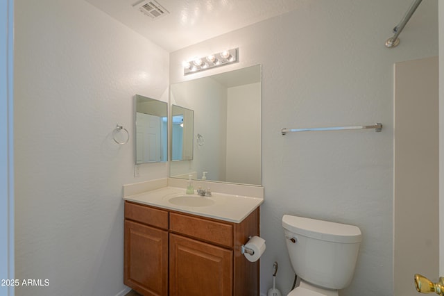 bathroom featuring visible vents, toilet, and vanity