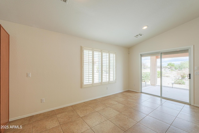 spare room featuring light tile patterned flooring, visible vents, baseboards, and vaulted ceiling