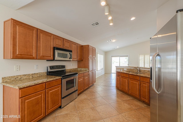 kitchen featuring brown cabinetry, visible vents, appliances with stainless steel finishes, and a sink