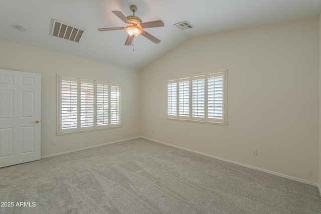 carpeted spare room featuring lofted ceiling, a healthy amount of sunlight, and visible vents