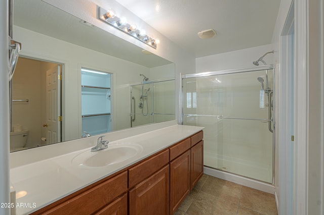 bathroom featuring tile patterned floors, toilet, a stall shower, and vanity