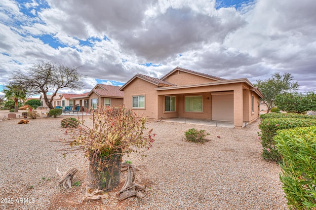 rear view of property with a tiled roof, a patio area, and stucco siding