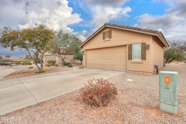 view of side of property with stucco siding, concrete driveway, an attached garage, and a tiled roof