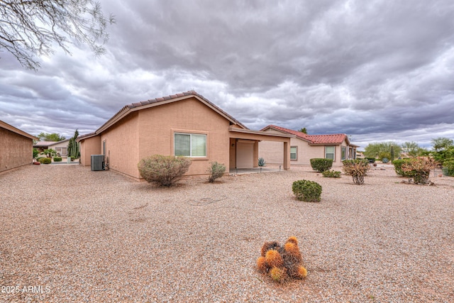 view of front of home featuring a tile roof, central AC, and stucco siding