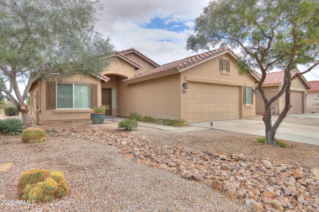 view of front of home featuring stucco siding, a garage, concrete driveway, and a tiled roof