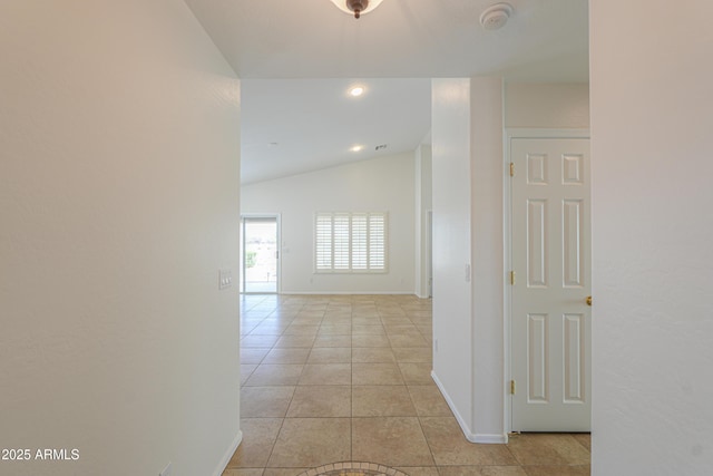 hallway featuring light tile patterned floors, baseboards, and vaulted ceiling